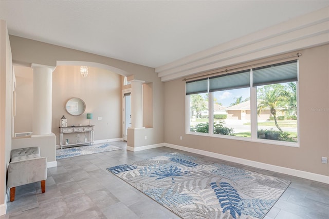 interior space featuring arched walkways, baseboards, and ornate columns