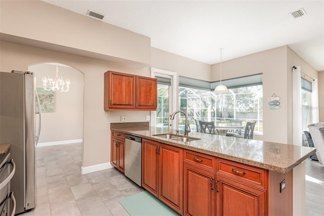 kitchen with visible vents, arched walkways, stainless steel appliances, a sink, and brown cabinets