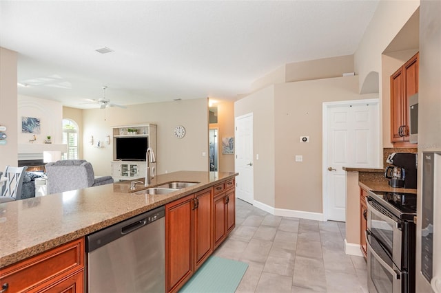 kitchen with a sink, light stone counters, brown cabinets, and appliances with stainless steel finishes