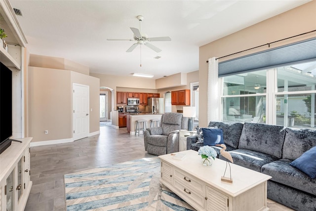 living room featuring visible vents, baseboards, light wood-type flooring, and ceiling fan