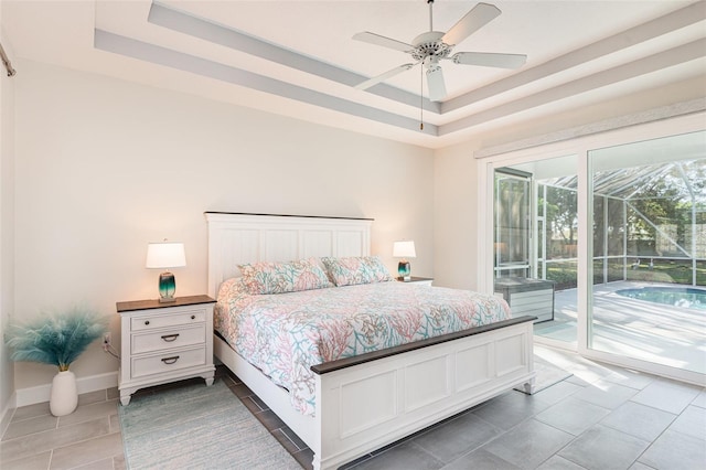 tiled bedroom featuring access to exterior, ceiling fan, baseboards, a tray ceiling, and a sunroom