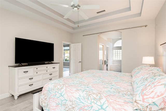 bedroom featuring a tray ceiling, multiple windows, and arched walkways