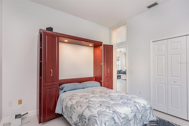 bedroom featuring light tile patterned floors, visible vents, and a closet