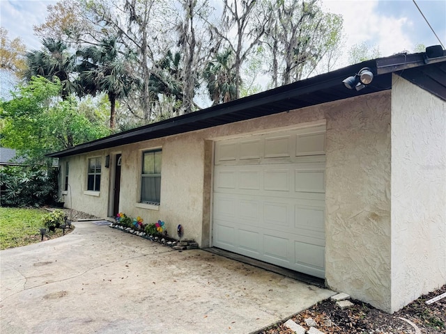 view of front facade with an attached garage, driveway, and stucco siding