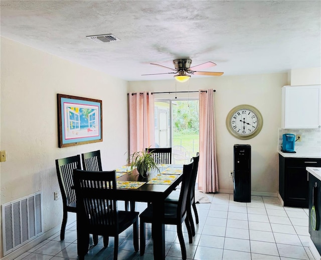 dining space with light tile patterned floors, a ceiling fan, visible vents, and a textured ceiling