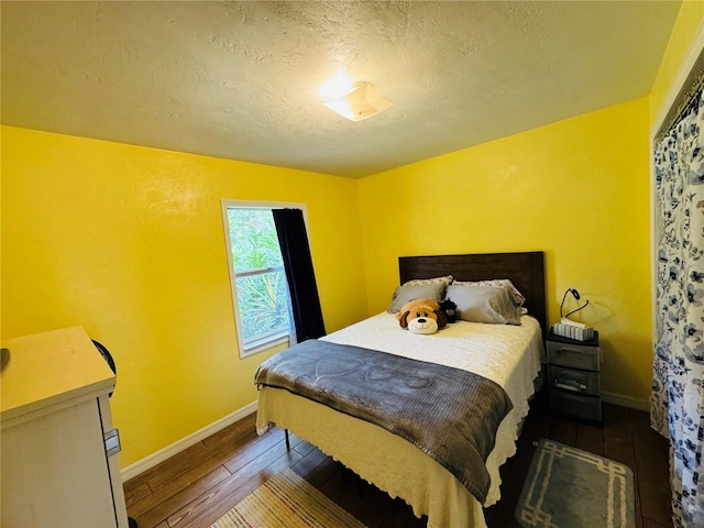 bedroom with baseboards, a textured ceiling, and hardwood / wood-style flooring