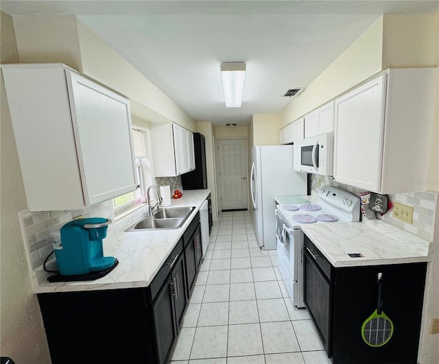 kitchen with visible vents, a sink, white cabinetry, white appliances, and dark cabinets