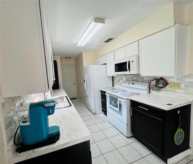 kitchen with visible vents, dark cabinets, decorative backsplash, white appliances, and a sink