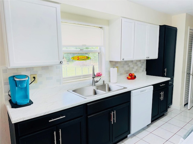 kitchen featuring backsplash, light tile patterned floors, white dishwasher, white cabinets, and a sink