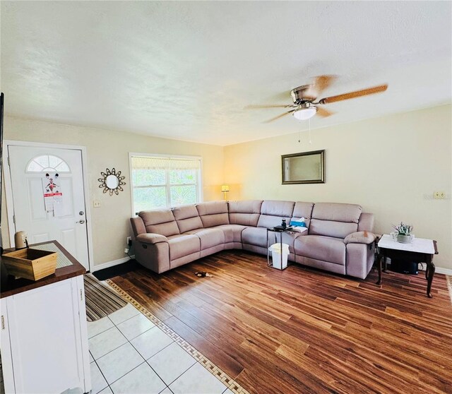 living room with baseboards, a textured ceiling, wood finished floors, and a ceiling fan