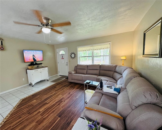 living room featuring a ceiling fan, wood finished floors, baseboards, and a textured ceiling