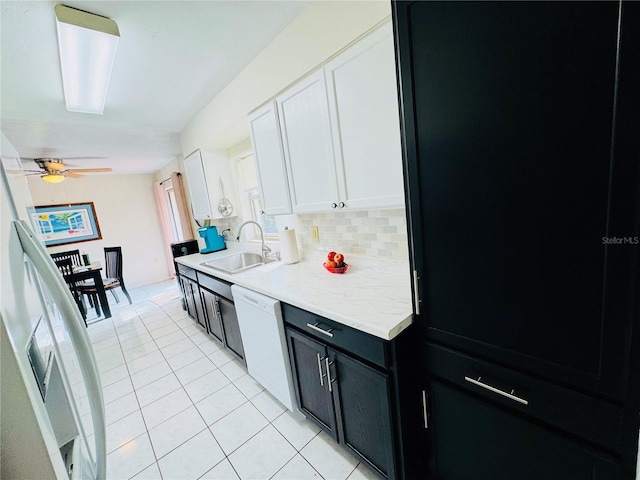 kitchen featuring backsplash, light countertops, white dishwasher, white cabinets, and a sink