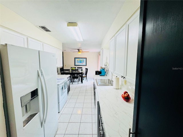 kitchen with white appliances, light tile patterned flooring, ceiling fan, a sink, and white cabinetry