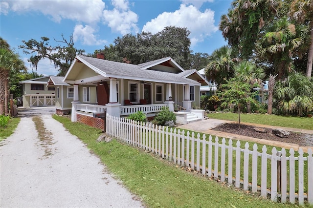 view of front of home featuring a front lawn, driveway, a fenced front yard, a porch, and ceiling fan