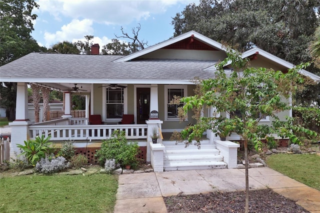 view of front of home featuring ceiling fan, a porch, a chimney, and roof with shingles