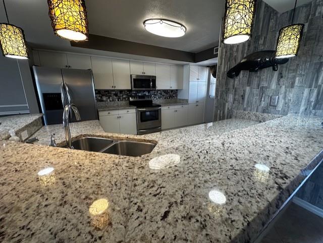 533 Marina Point Dr Unit 533, Daytona Beach, FL 32114 - kitchen with light stone counters, backsplash, white cabinets, appliances with stainless steel finishes, and a sink