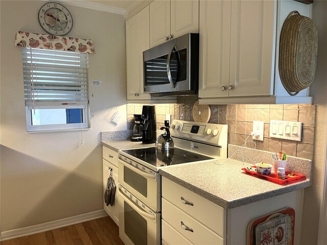 kitchen with range with two ovens, backsplash, stainless steel microwave, baseboards, and ornamental molding