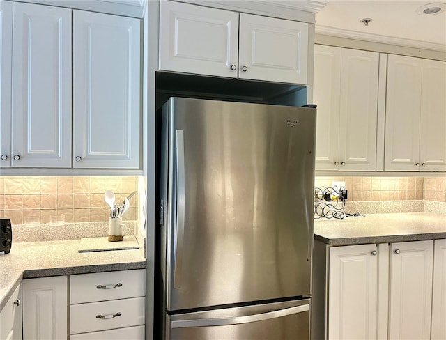 kitchen featuring white cabinetry, light countertops, decorative backsplash, and freestanding refrigerator