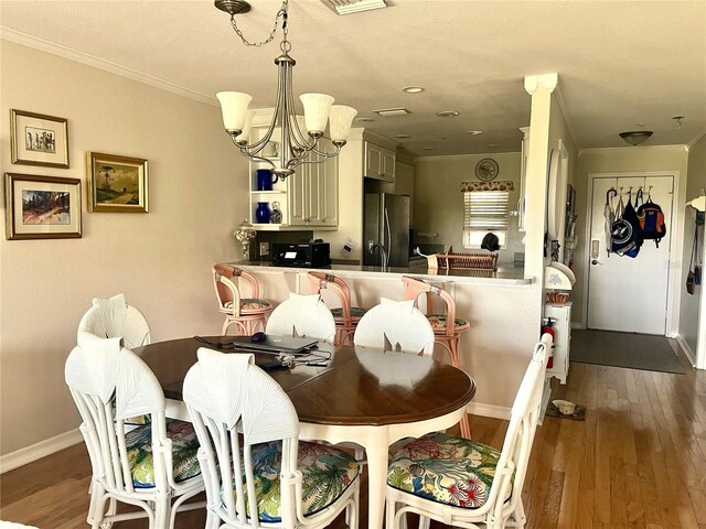 dining room with baseboards, dark wood-style floors, a notable chandelier, and ornamental molding