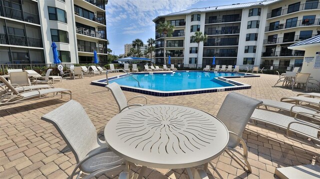 community pool with a patio area and fence
