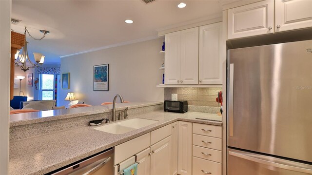 2700 N Peninsula Ave Unit 113, New Smyrna Beach, FL 32169 - kitchen featuring appliances with stainless steel finishes, a sink, white cabinetry, a chandelier, and ornamental molding