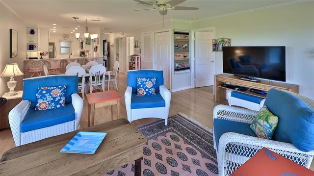2700 N Peninsula Ave Unit 113, New Smyrna Beach, FL 32169 - living area with wood finished floors, a chandelier, a ceiling fan, and ornamental molding