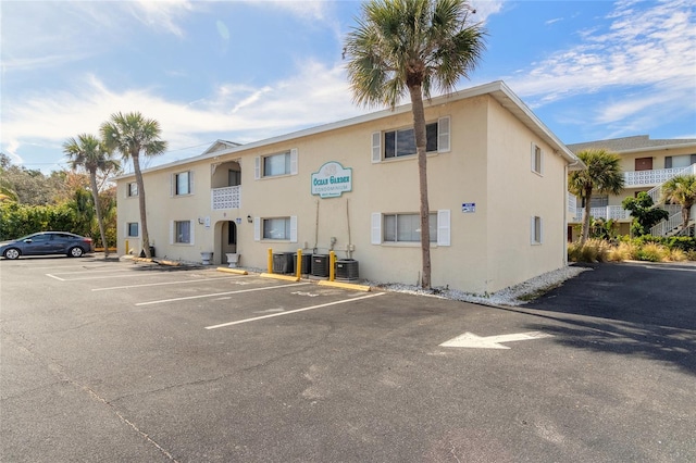 view of property featuring uncovered parking and central AC