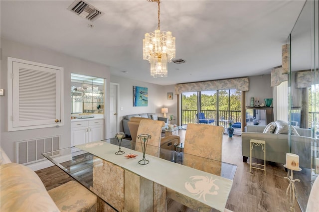 dining space featuring visible vents, wood finished floors, and a chandelier