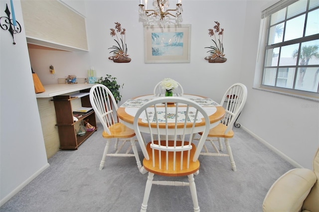 carpeted dining area featuring baseboards and an inviting chandelier