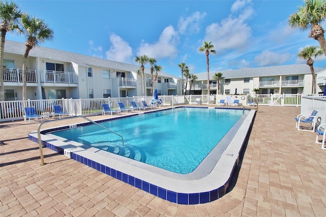 community pool with a residential view, a patio, and fence