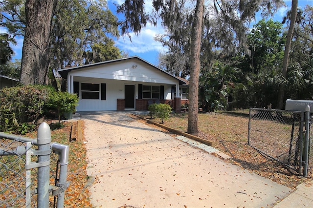 bungalow-style house featuring covered porch, concrete driveway, and fence