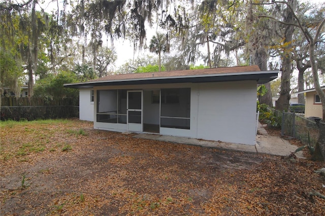 rear view of property featuring fence and a sunroom