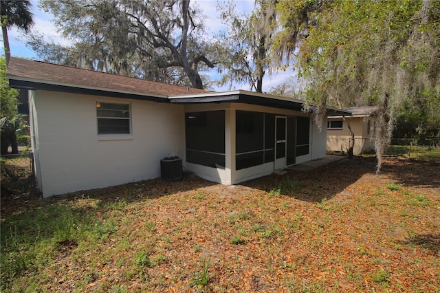 rear view of house featuring cooling unit, fence, concrete block siding, and a sunroom