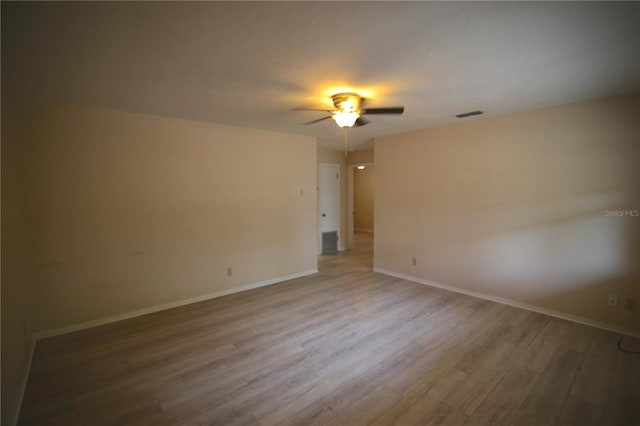 spare room featuring ceiling fan, visible vents, baseboards, and wood finished floors