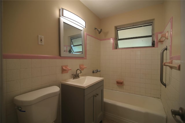 full bathroom with a wainscoted wall, toilet, vanity, shower / tub combination, and tile walls