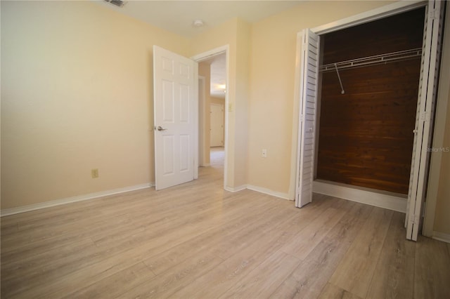 unfurnished bedroom featuring a closet, visible vents, baseboards, and light wood finished floors