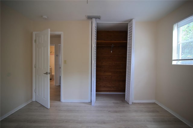 unfurnished bedroom with a closet, visible vents, baseboards, and light wood-style floors