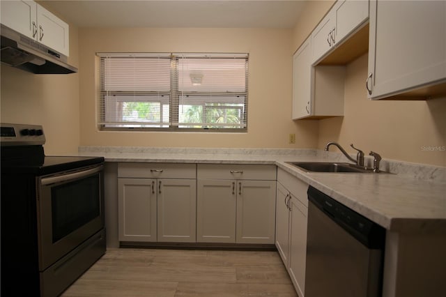 kitchen featuring a sink, light countertops, under cabinet range hood, and stainless steel appliances