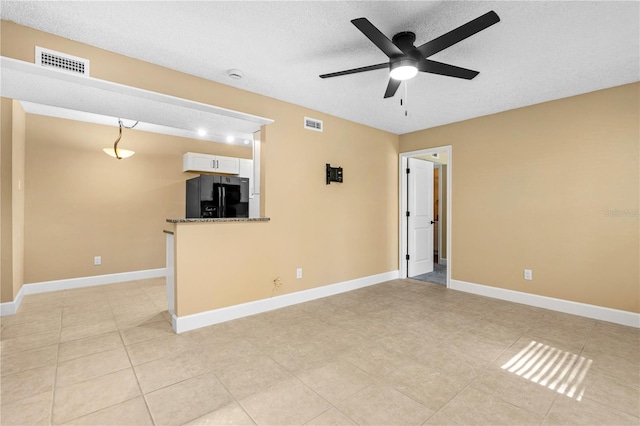 unfurnished living room with visible vents, a textured ceiling, baseboards, and a ceiling fan