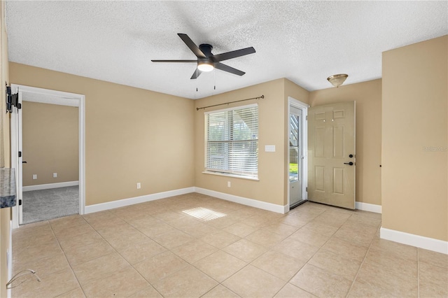 entryway with light tile patterned floors, baseboards, a textured ceiling, and a ceiling fan