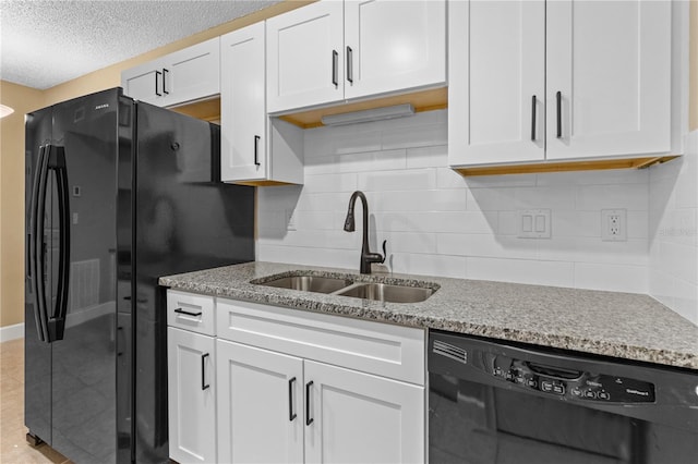 kitchen with black appliances, white cabinets, light stone counters, and a sink