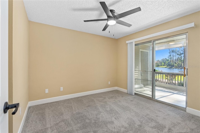 unfurnished room with a water view, a textured ceiling, carpet floors, baseboards, and ceiling fan