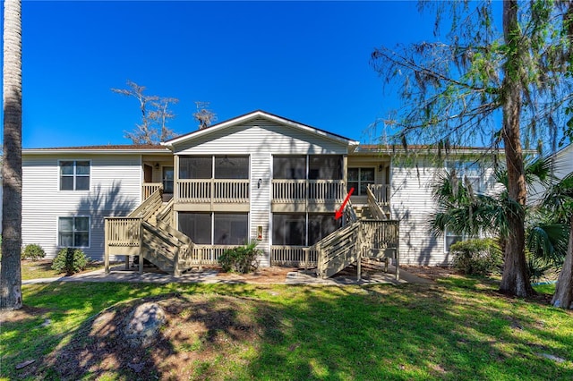 back of property with stairs, a yard, and a sunroom