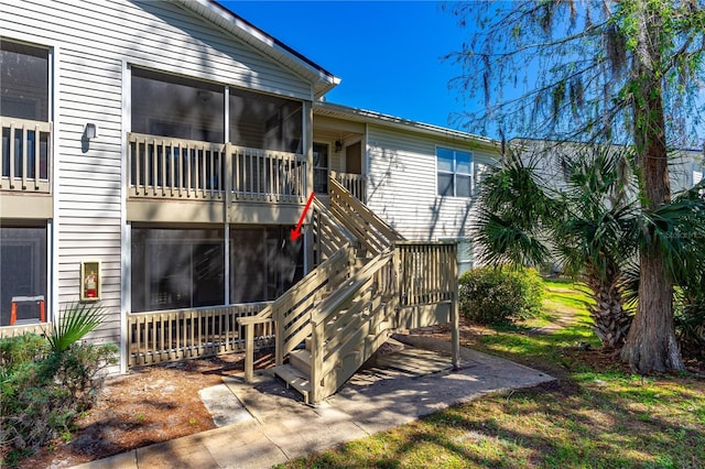 rear view of property featuring stairs and a sunroom