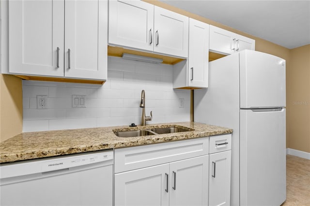 kitchen featuring tasteful backsplash, light stone counters, white appliances, white cabinetry, and a sink