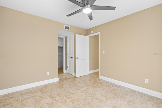 empty room featuring light tile patterned floors, visible vents, ceiling fan, and baseboards