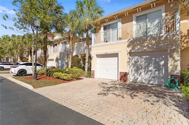 view of front of property with decorative driveway, an attached garage, and stucco siding