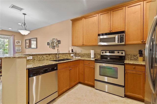 kitchen featuring visible vents, light stone counters, a peninsula, stainless steel appliances, and a sink