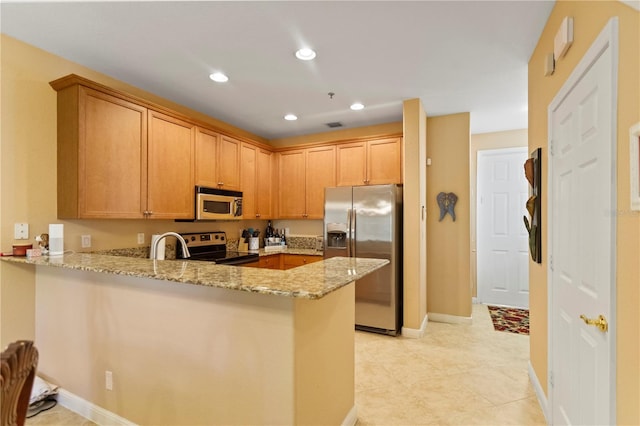 kitchen with a peninsula, light stone counters, recessed lighting, and appliances with stainless steel finishes