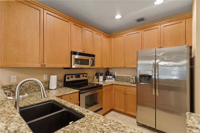 kitchen featuring a sink, stainless steel appliances, light stone countertops, and visible vents